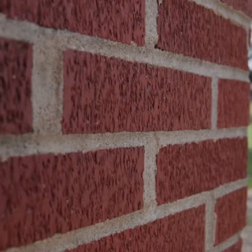 Handheld close up and slow motion view of vintage red brick pattern on outdoor surface, with warm and white textures
